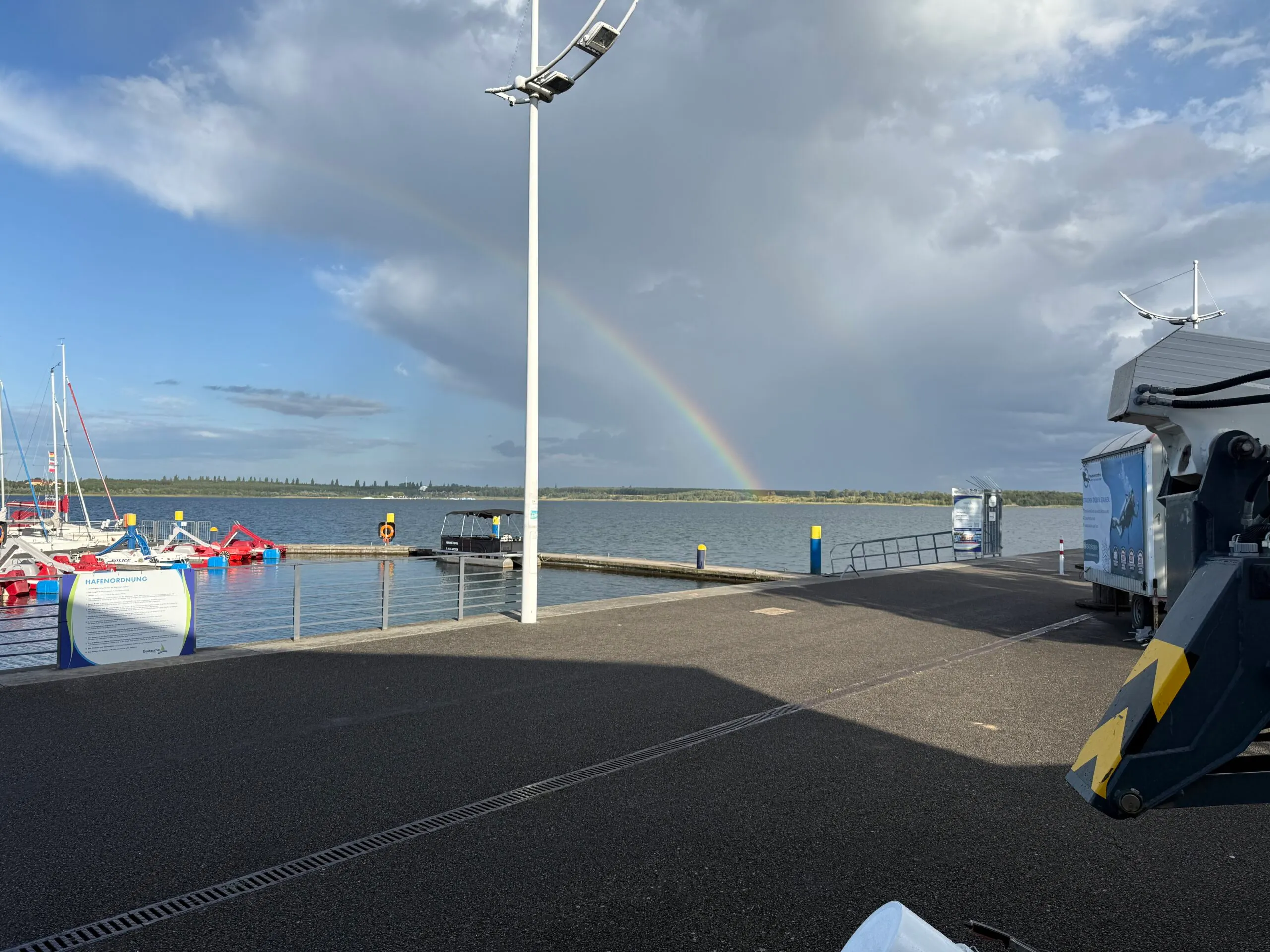 Hafengebäude der Bernstein Marina mit Regenbogen über dem See
